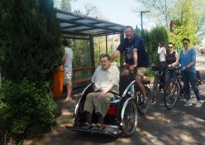 Zwei Männer sitzen auf einer Fahrradrikscha, einer fährt, der andere sitzt